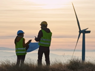 Two wind turbine engineers at sunset