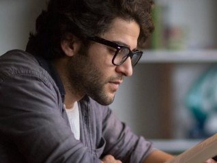Knowledge and researching zoomed in image of man reading and using laptop