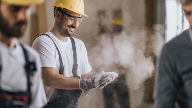 Happy construction worker with dusty gloves