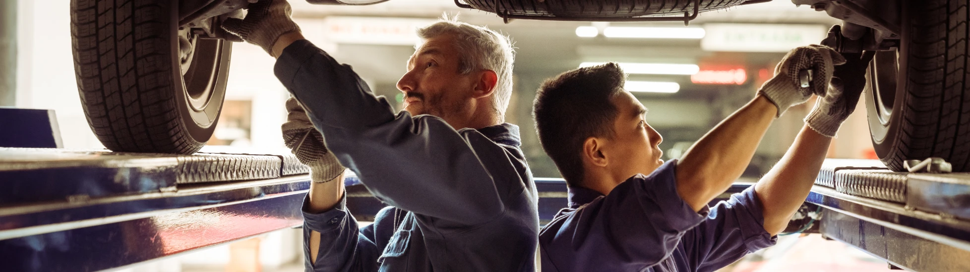 Two mechanics working underneath a car