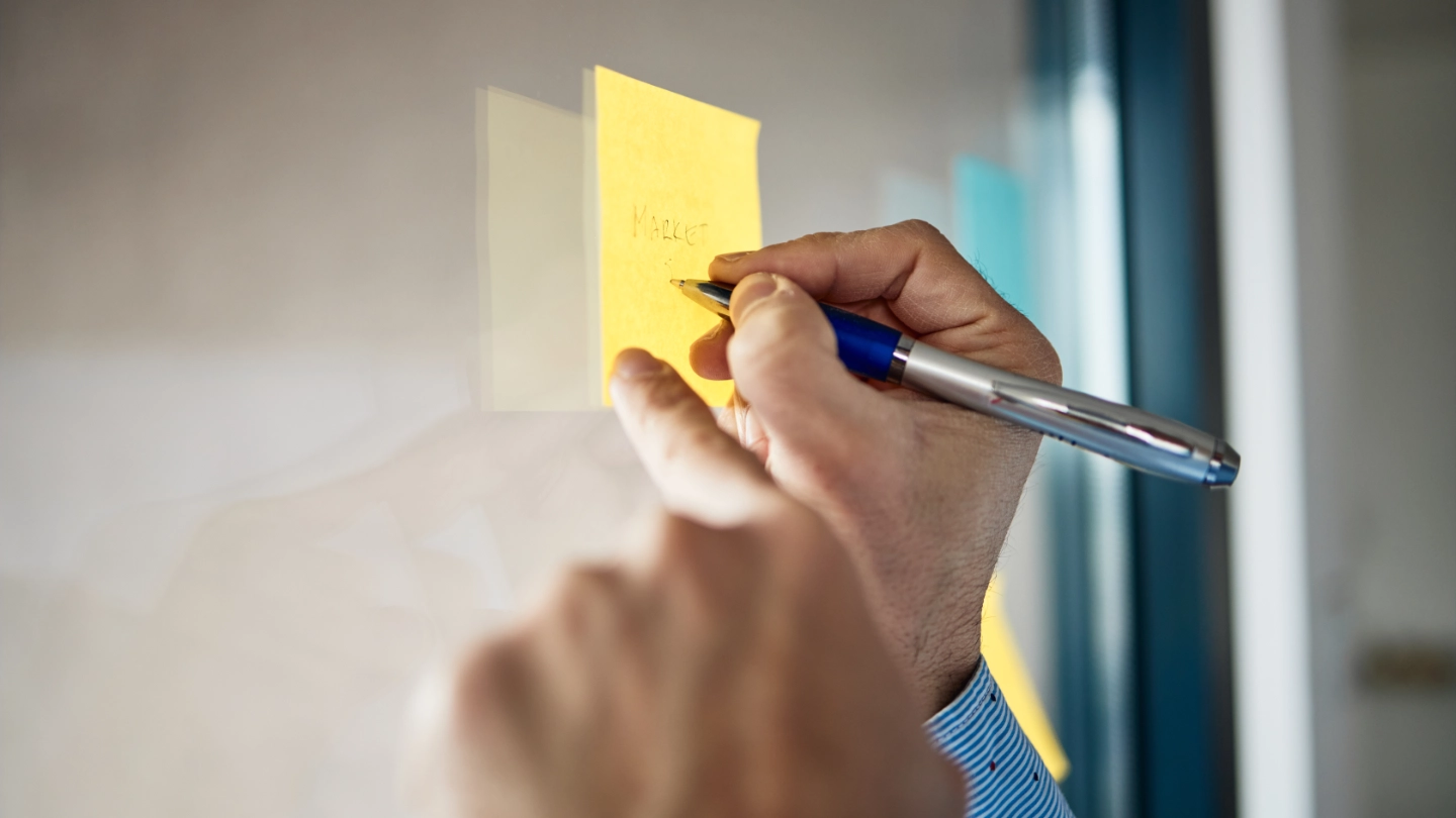 hands writing on post it note hands writing on post it note