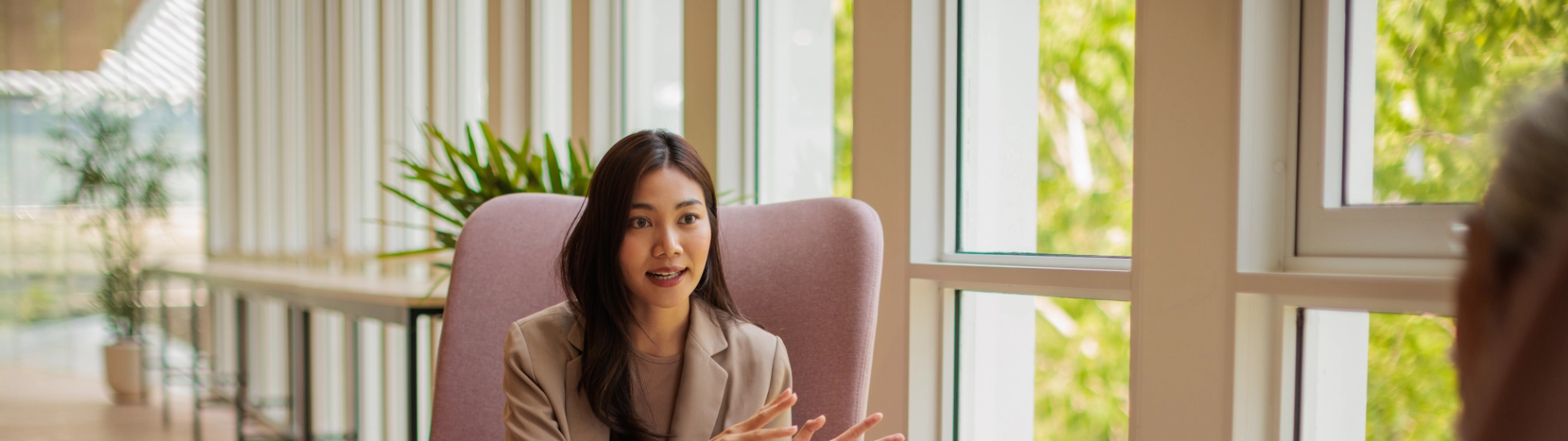 Asian Lady sitting in a chair talking to a colleague, sharing knowledge