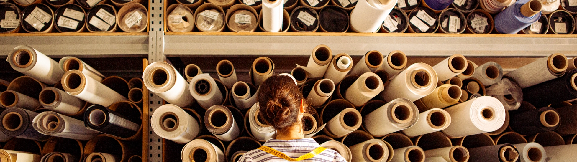 Female textile worker examining reels of fabric